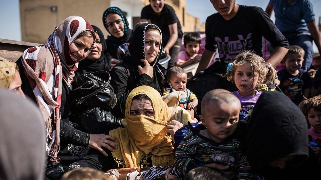 Syrian refugees cross the Syria-Turkey border on 22 June 2015, as they return to the northern Syrian town of Tal Abyad