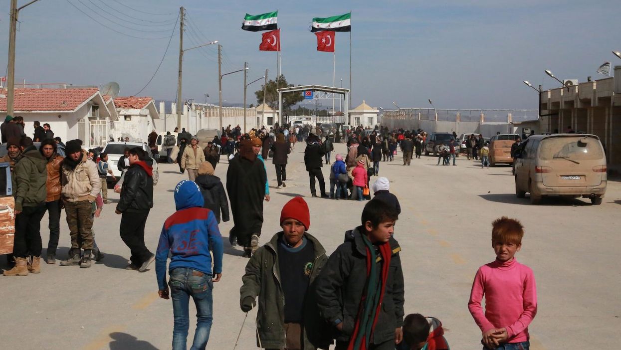 Syrians fleeing Aleppo wait at the crossing on the border between Syria and Turkey, on 5 February 2016