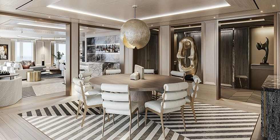 The dining room of the Regent Suite on board the Seven Seas Splendor. It has a round table in the middle and a striped rug on the floor.