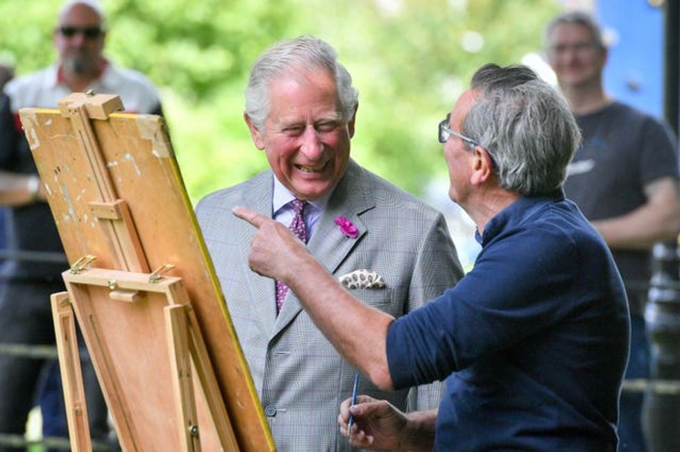 The King chats to an artist working at their easel on a visit to Dorset