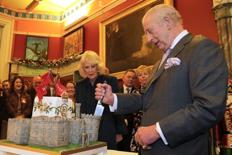 The King cuts a cake shaped as a castle during a visit to Cyfarthfa Castle in Merthyr Tydfil, South Wales