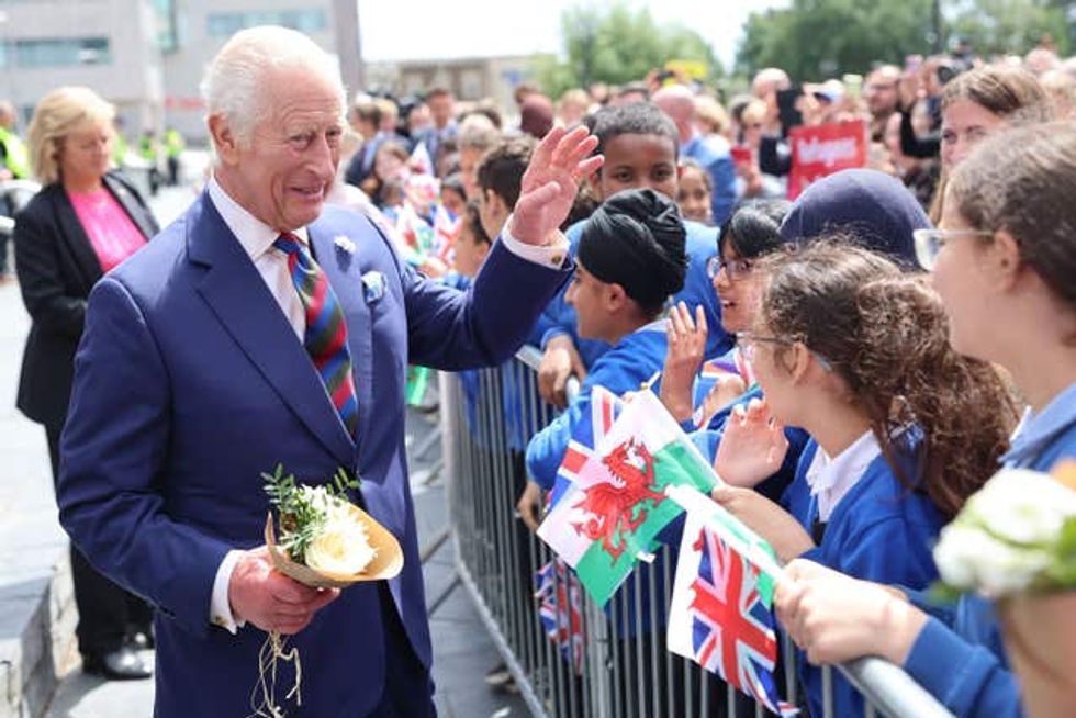 The King waves as he accepts flowers from members of the public outside the Senedd