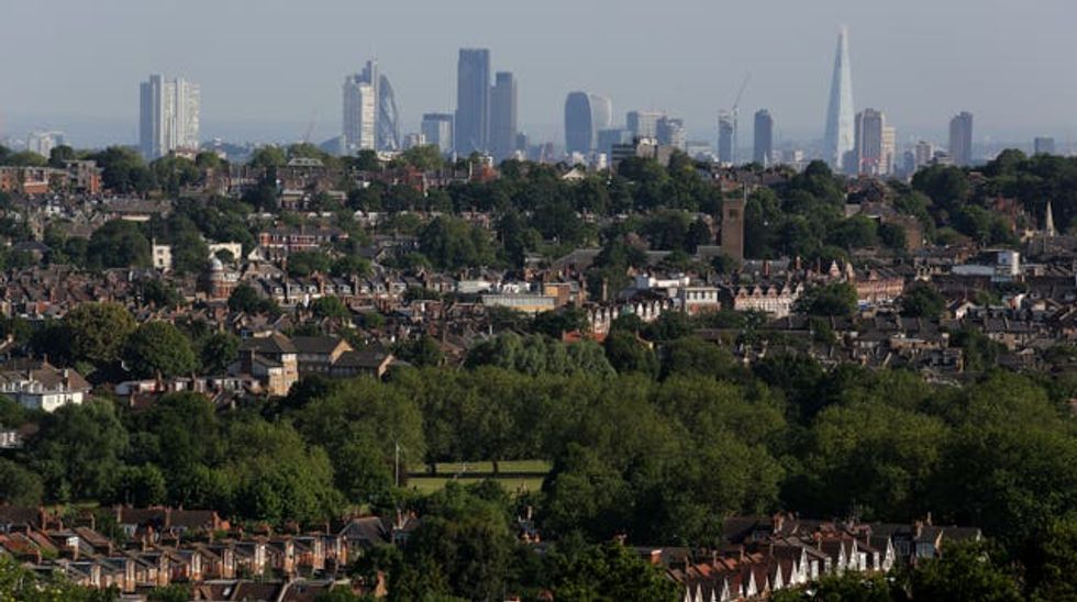 The London skyline seen from Alexandra Palace with trees and houses in the foreground and city skyscrapers behind