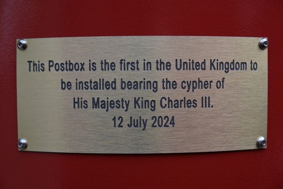 The plaque with wording announcing the postbox is the first in the UK with the King's cypher