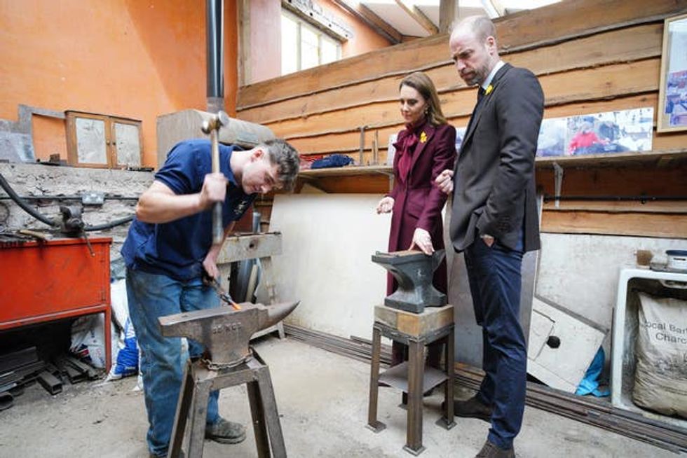 The Prince and Princess of Wales watching metal being forged during a visit to the Hanging Gardens