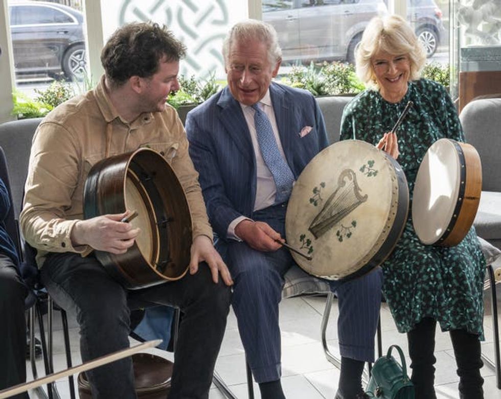 The Prince of Wales (centre) and Duchess of Cornwall play the bodhran