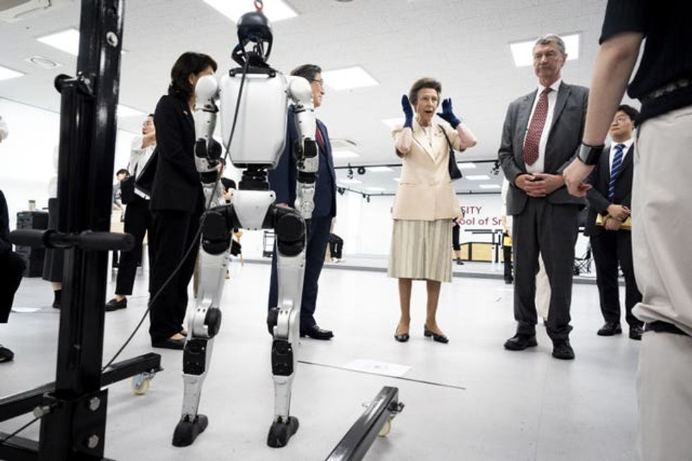 The princess gestures as she chats to the university team in front of the robot