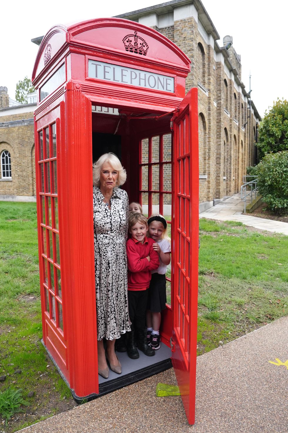 Queen bundles into phone box with schoolchildren as she visits gallery