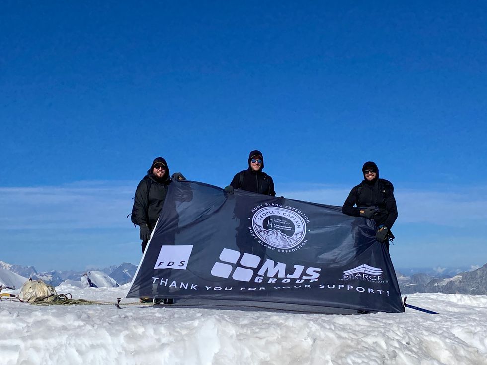 The trio at the summit of Monte Rosa, holding a banner
