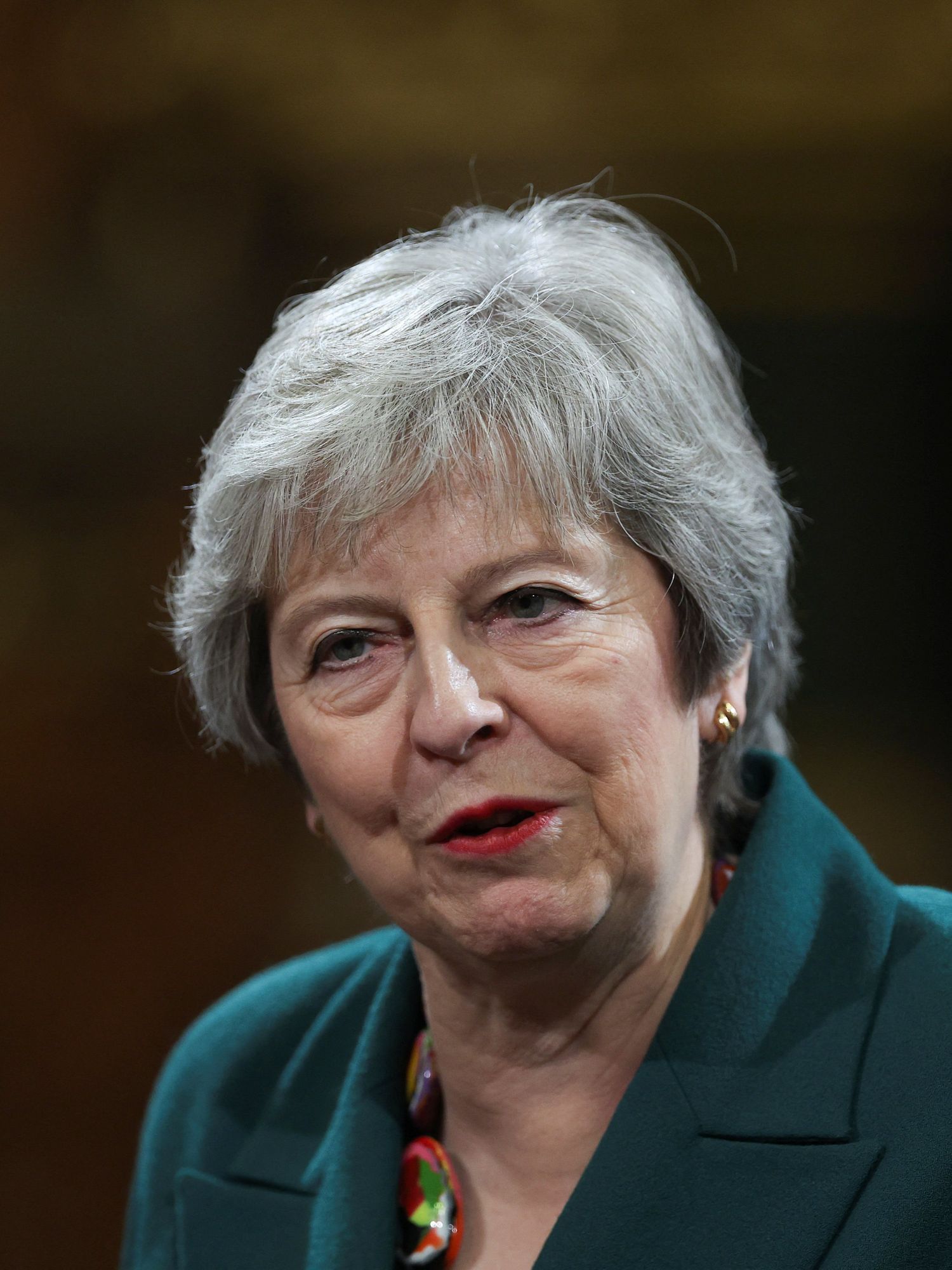 Theresa May, a white woman with short silver hair and a turquoise jacket.