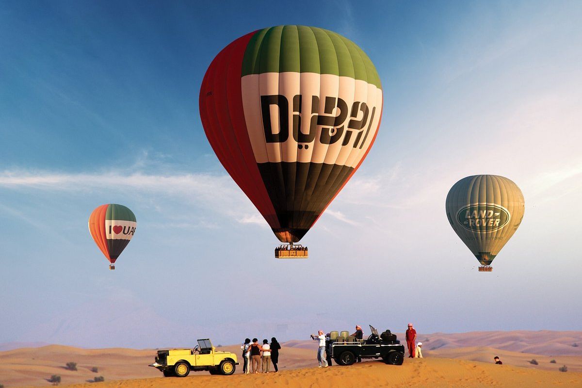 Three hot air balloons float in the sky across the desert