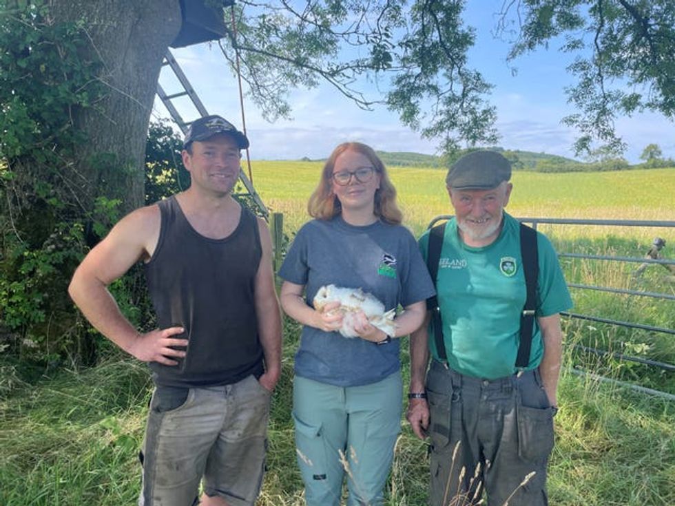 Three people standing with one holding a barn owl