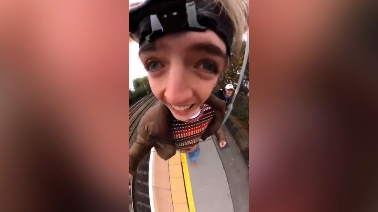Shocking viral video sees woman lie down on rail tracks and talk on phone as train passes over her