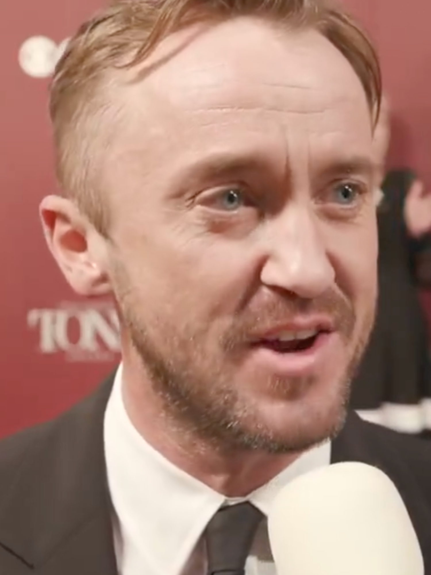 Tom Felton in a black suit, speaking to Variety on the red carpet at the Tony Awards.