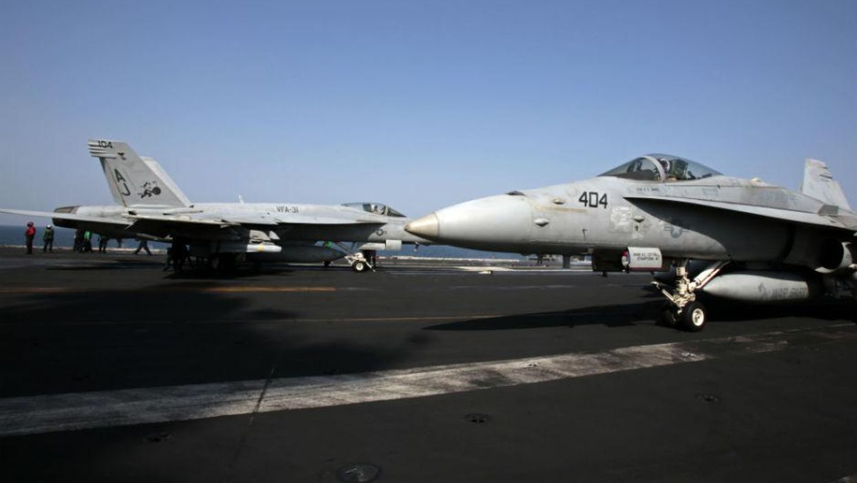 Two FA-18 fighter jets prepare to take-off for Iraq from the USS George HW Bush