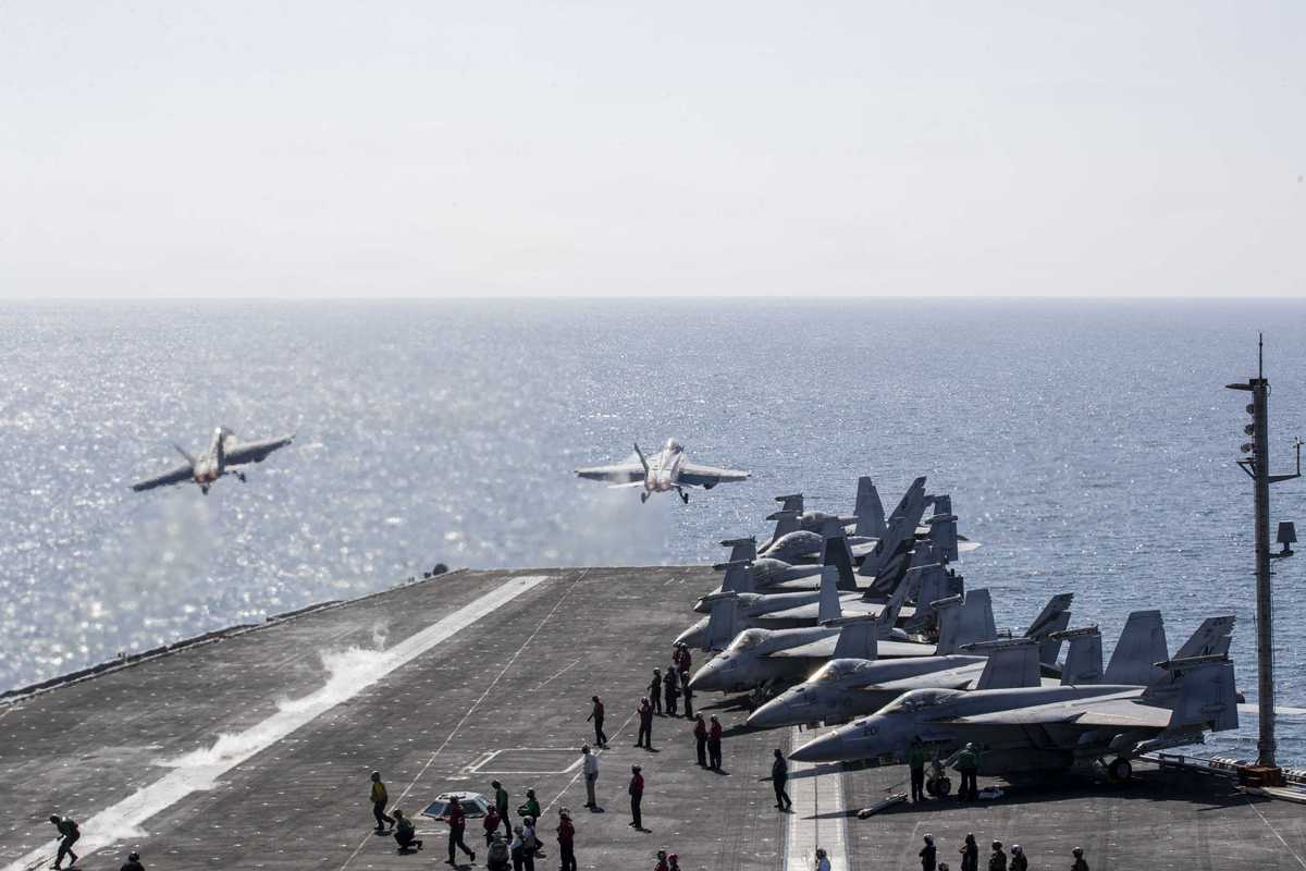Two jets launch from the USS Abraham Lincoln at sea.