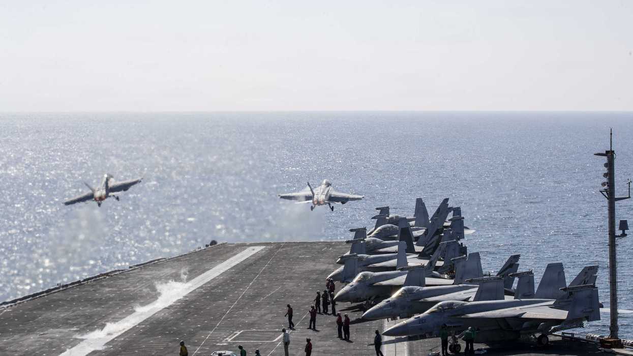 Two jets launch from the USS Abraham Lincoln at sea.