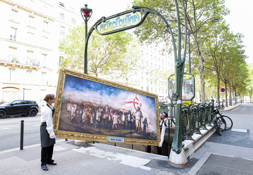 Two people carrying the painting trying to take it down the stairs of Paris' Metro