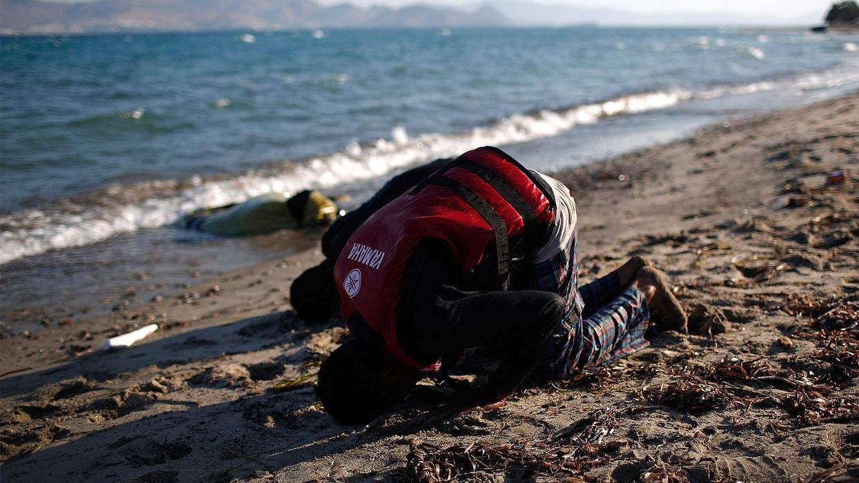 Two people from Pakistan pray on the beach after arriving in Kos, Greece on 29 August 2015