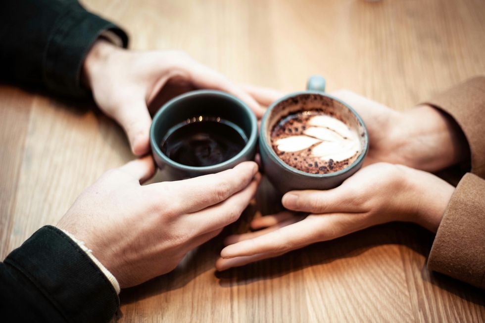 Two people holding ceramic mugs with coffee
