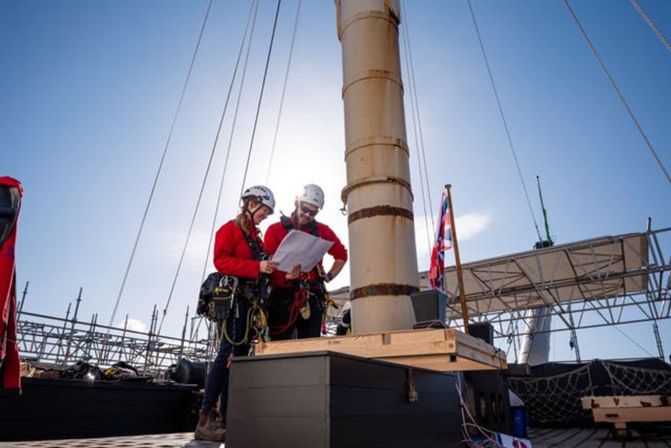Two people in red at the bottom of a mast