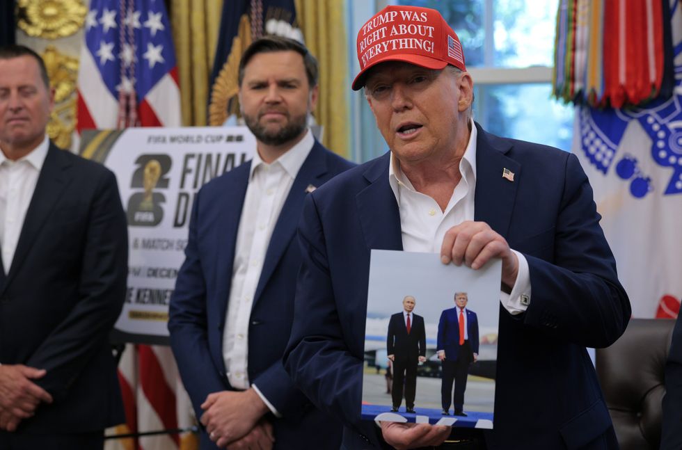 U.S. President Donald Trump holds a photograph he said was given to him as a gift by Russian President Vladimir Putin in the Oval Office at the White House August 22, 2025 in Washington, DC. Trump announced the FIFA World Cup 2026 draw will take place at The Kennedy Center