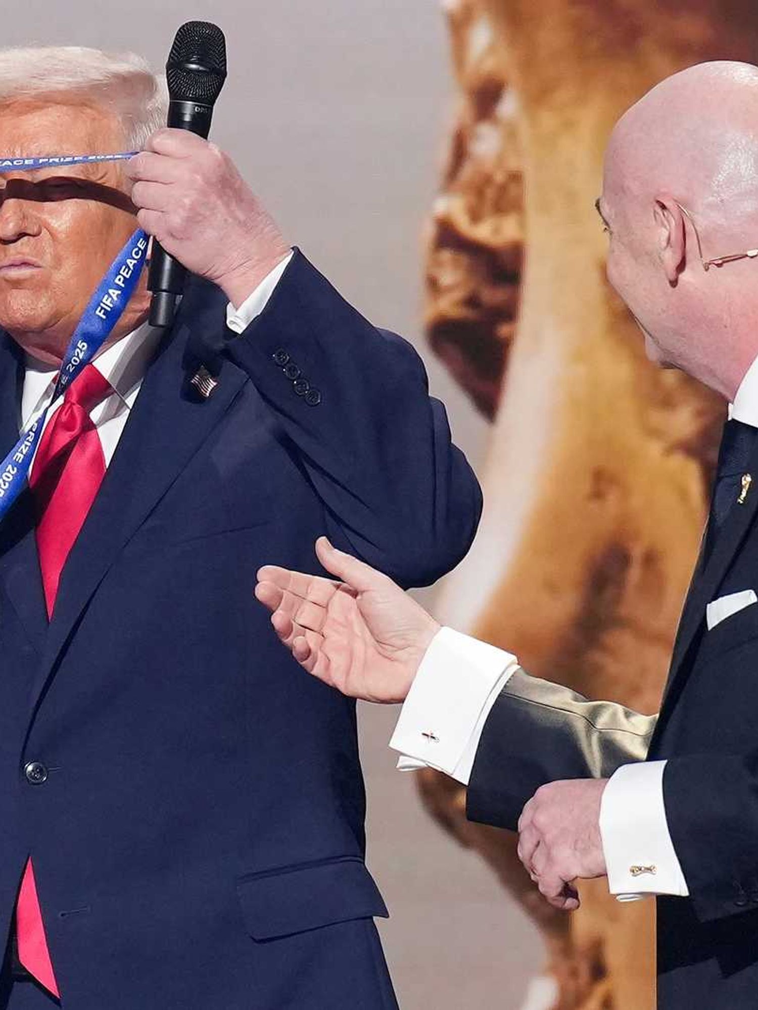 U.S. President Donald Trump places the FIFA Peace Prize around his neck after receiving it from FIFA President Gianni Infantino (R) at the FIFA World Cup 2026 Official Draw at the John F. Kennedy Center