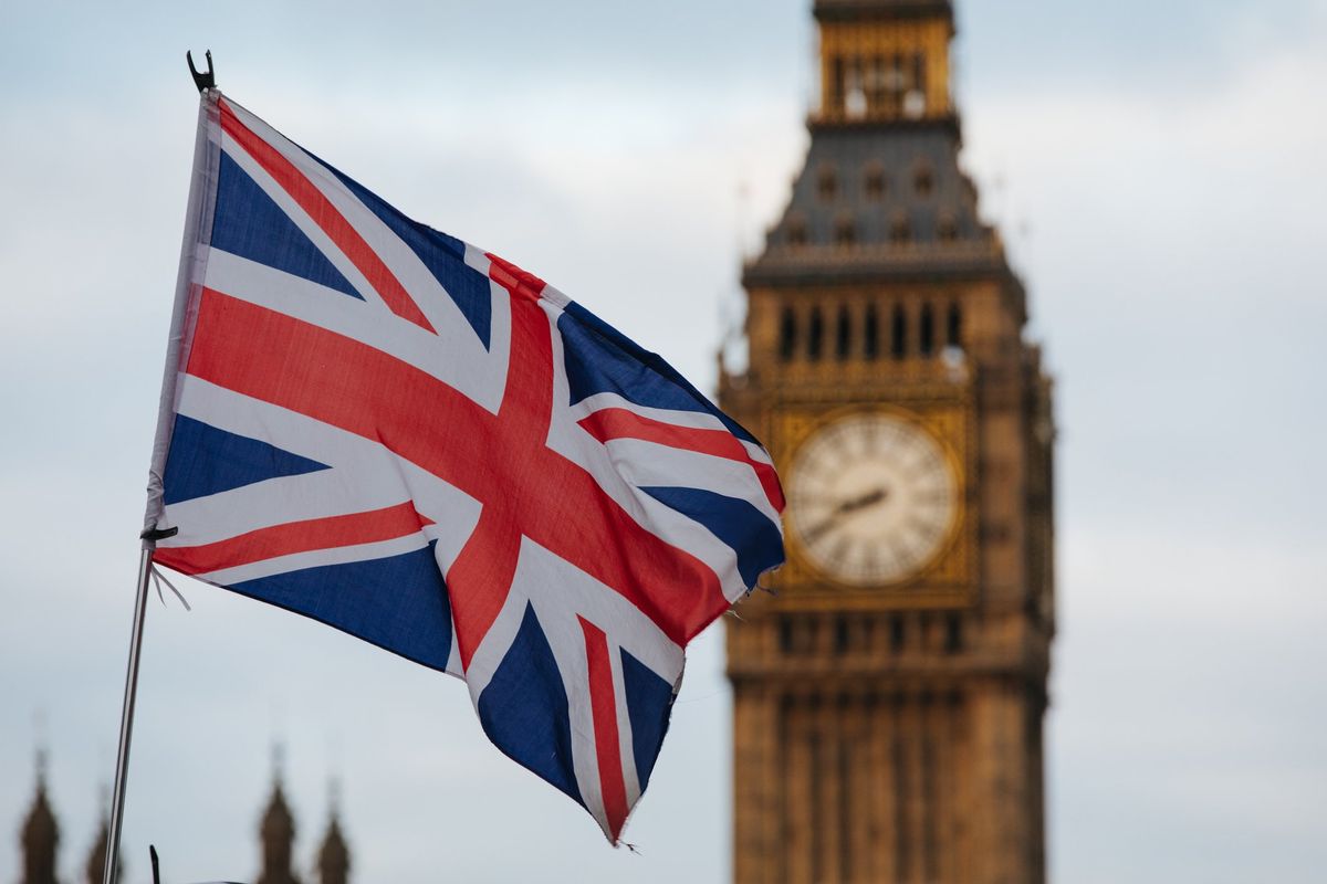 Union Jack flag waves in the air with the Elizabeth Tower (Big Ben) visible in the background.