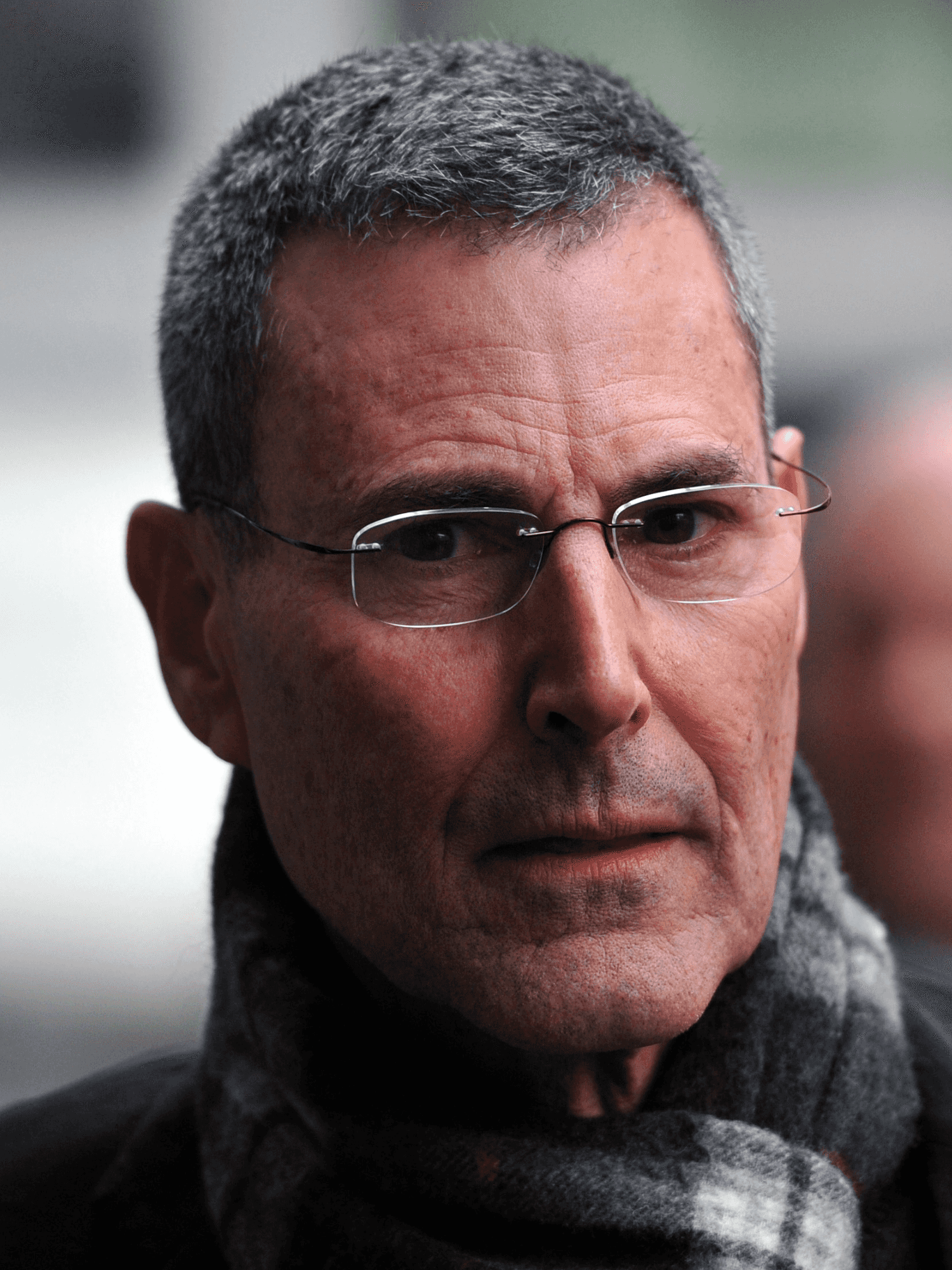Uri Geller, an Israeli-British man with short grey hair, rectangular glasses, a grey scarf and black coat, gives the camera a slightly concerned look as he's photographed in London.