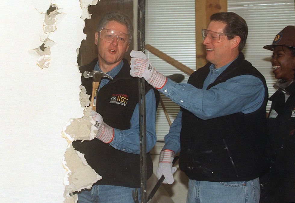 US President Bill Clinton (L), Vice President Al Gore (C) and an unidentified Americorp volunteer (R) tear down a wall to begin renovation of the Regency House, a senior health center, 18 January in Washington.  Clinton, along with Vice President Al Gore, announced the largest lending discrimination settlement at the center during the 1999 Martin Luther King Day Service Project. Picture: