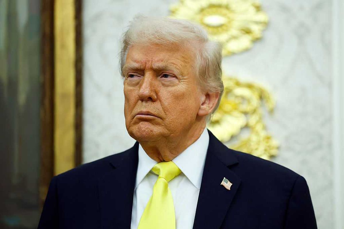 US president Donald Trump, in a black suit with fluorescent yellow tie, frowns as he looks at something off-camera to his right.