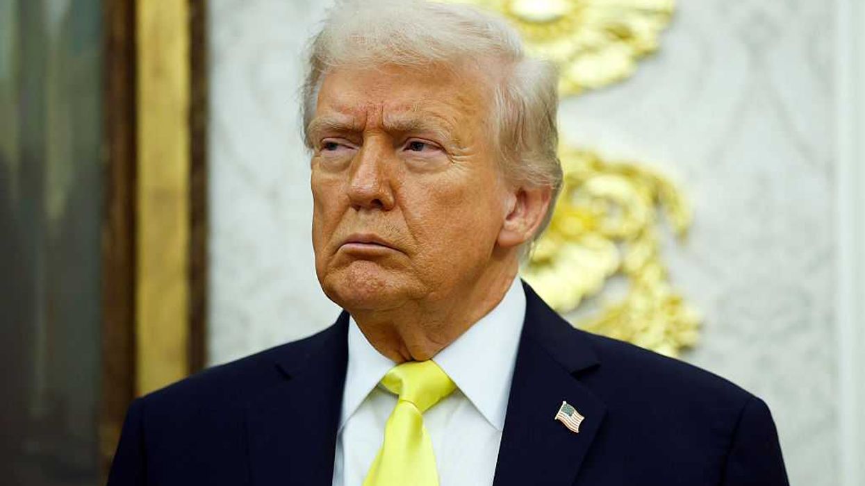 US president Donald Trump, in a black suit with fluorescent yellow tie, frowns as he looks at something off-camera to his right.