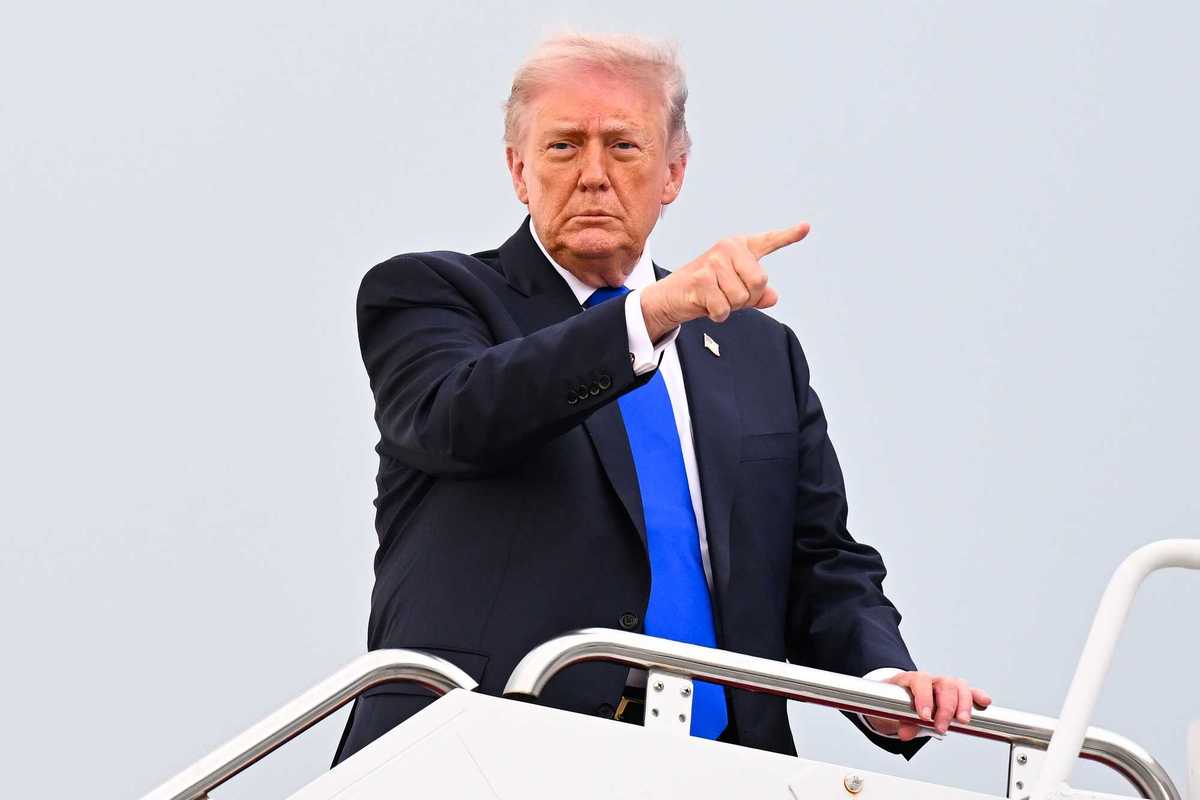 US President Donald Trump points at something with his right index finger while boarding Air Force One.