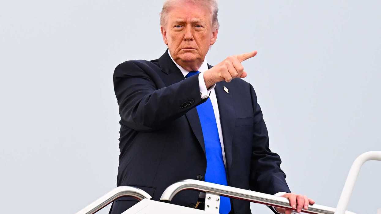 US President Donald Trump points at something with his right index finger while boarding Air Force One.