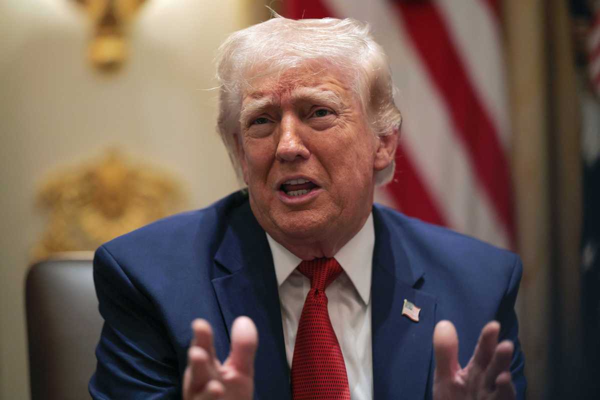 US president Donald Trump sits in a chair and speaks inside the White House.