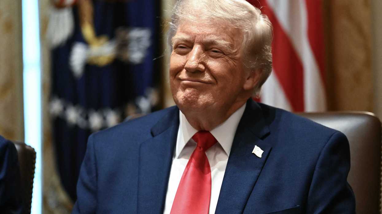 US president Donald Trump smiles smugly while sitting in the Cabinet Room of the White House.