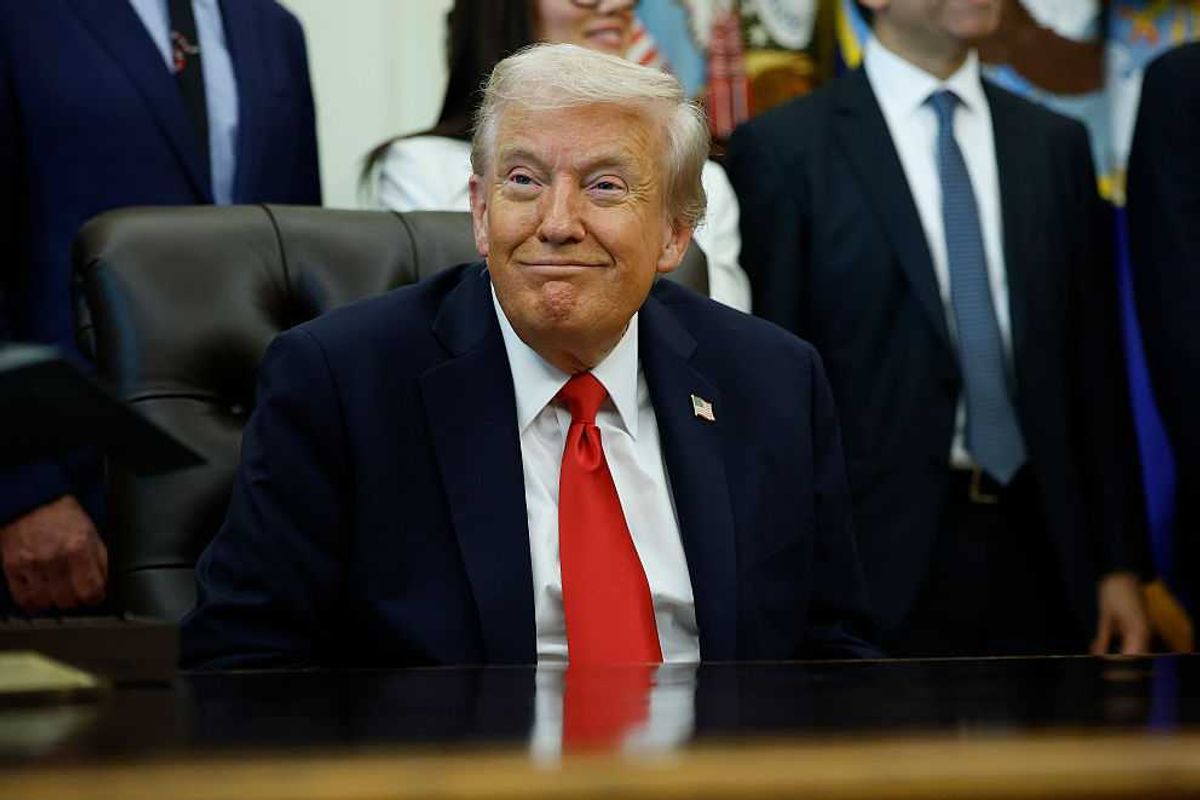 US president Donald Trump smirks behind the Oval Office desk.