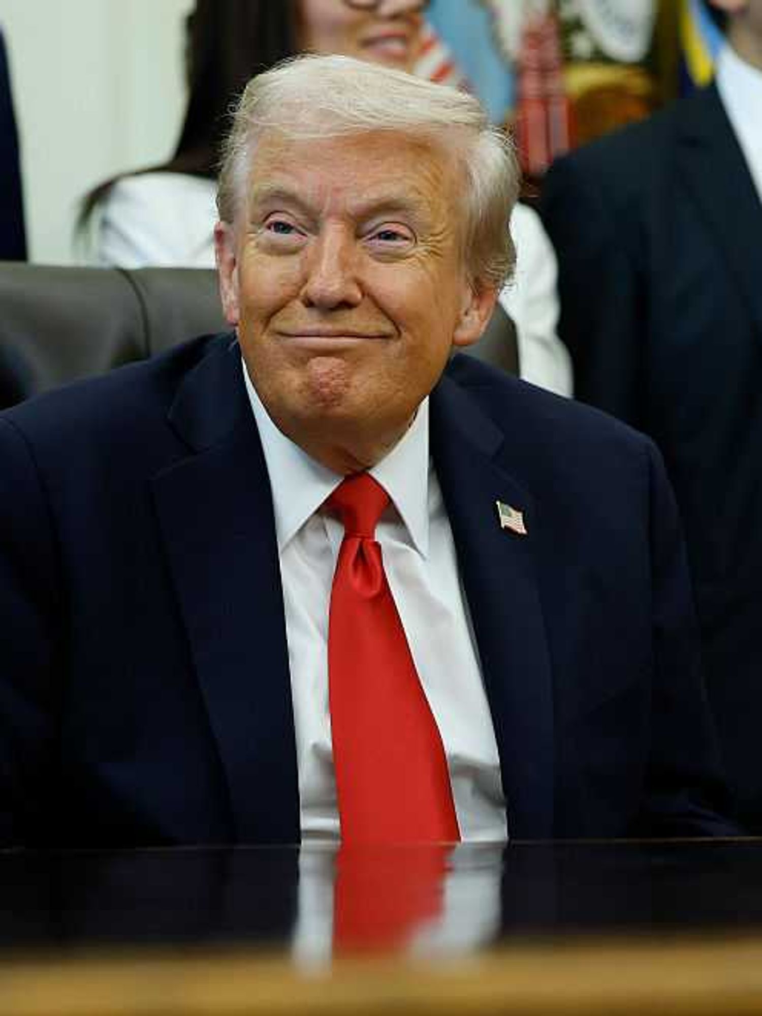 US president Donald Trump smirks behind the Oval Office desk.