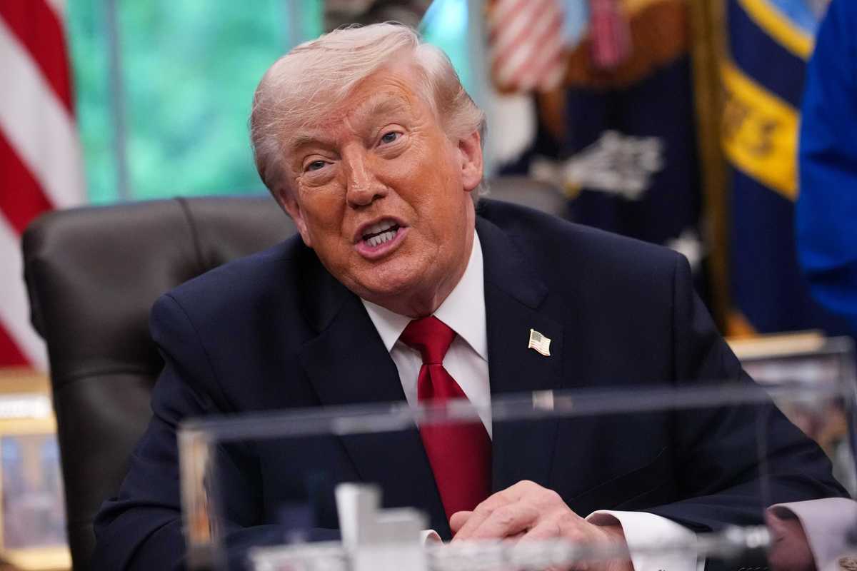 US President Donald Trump talking to reporters behind the Resolute Desk in the Oval Office.