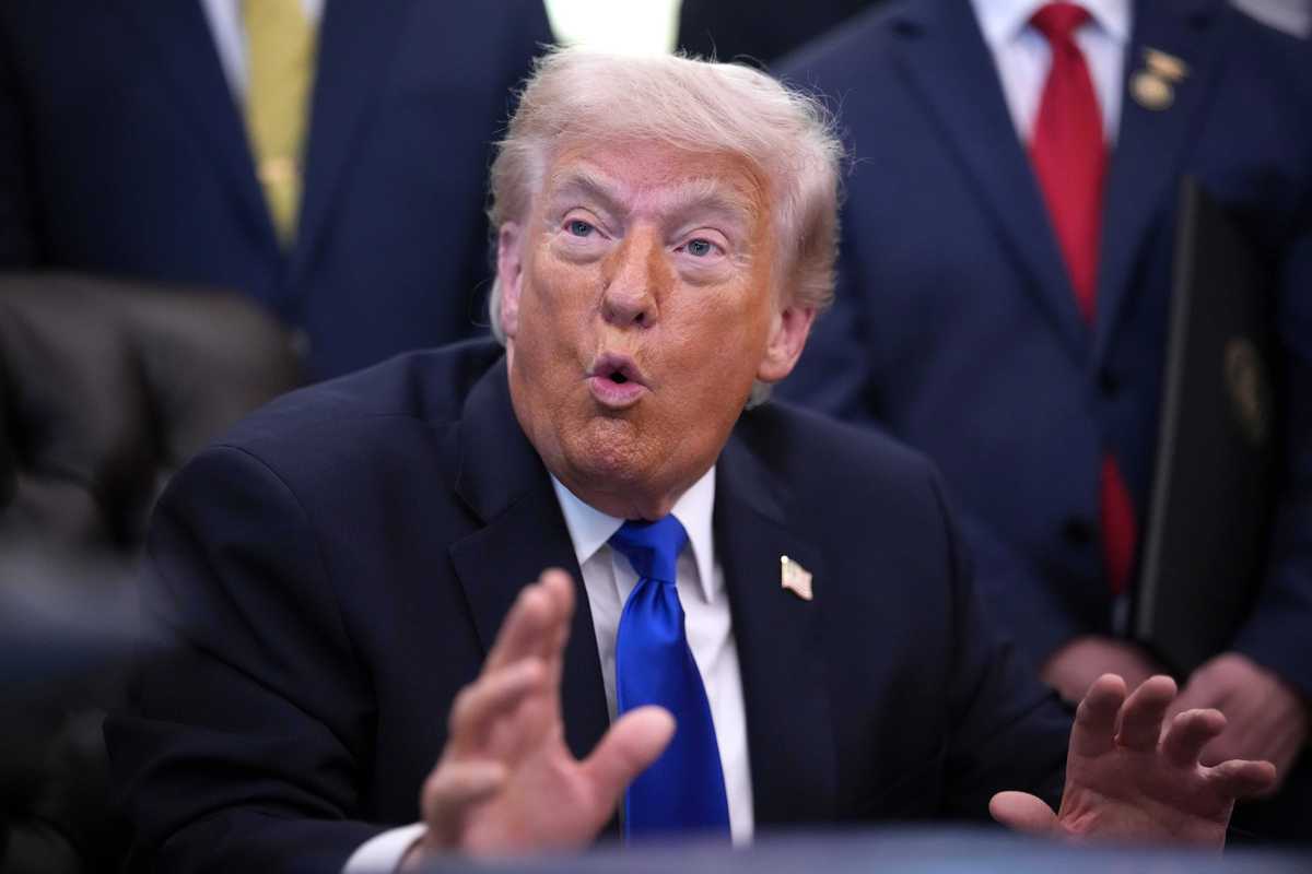 US President Donald Trump talking to reporters in the Oval Office behind the Resolute Desk.