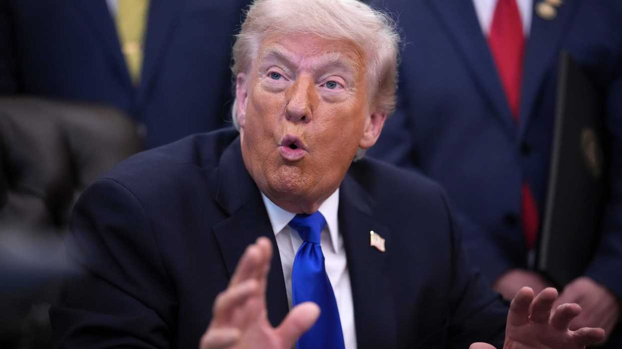 US President Donald Trump talking to reporters in the Oval Office behind the Resolute Desk.