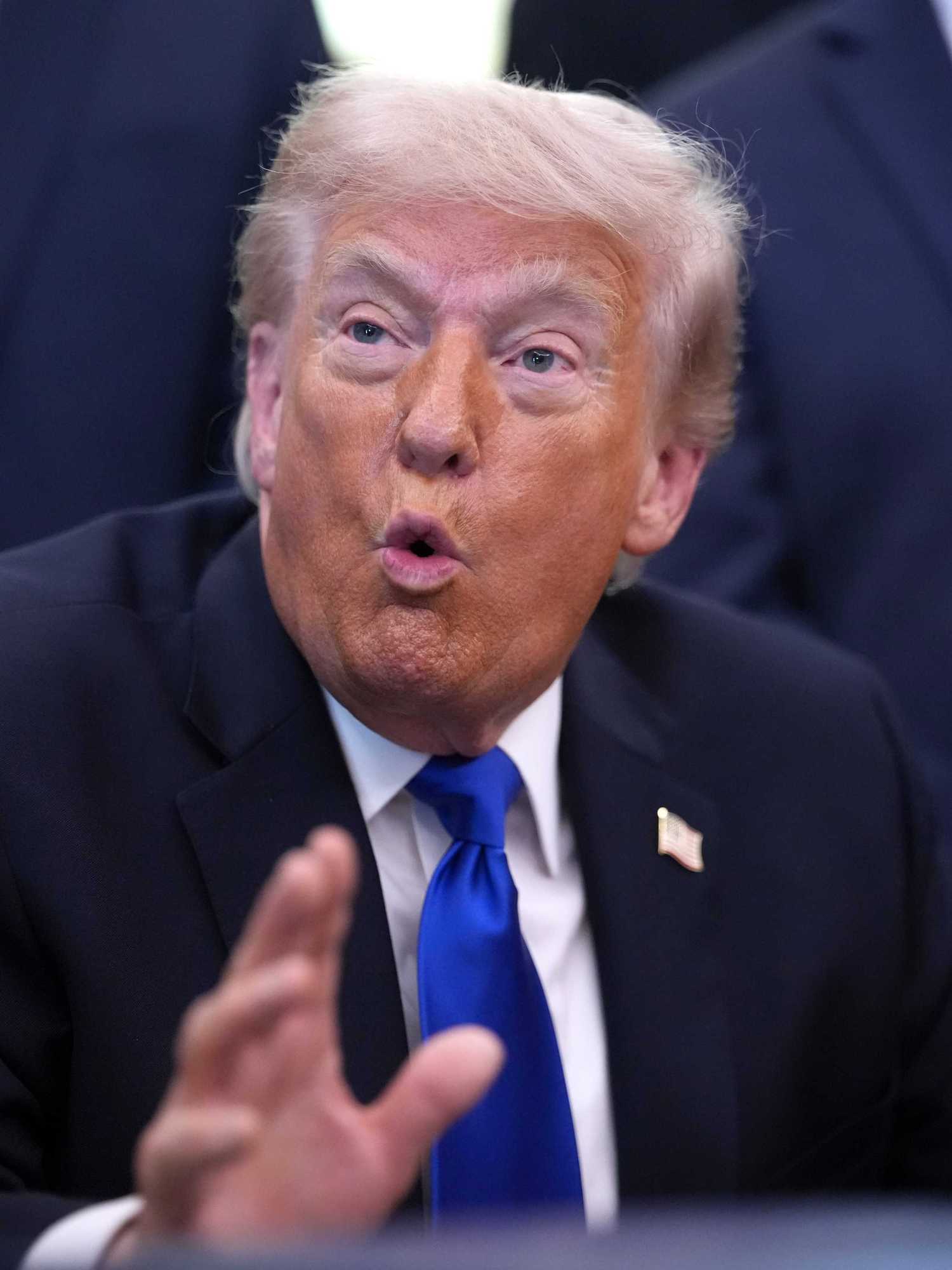 US President Donald Trump talking to reporters in the Oval Office behind the Resolute Desk.