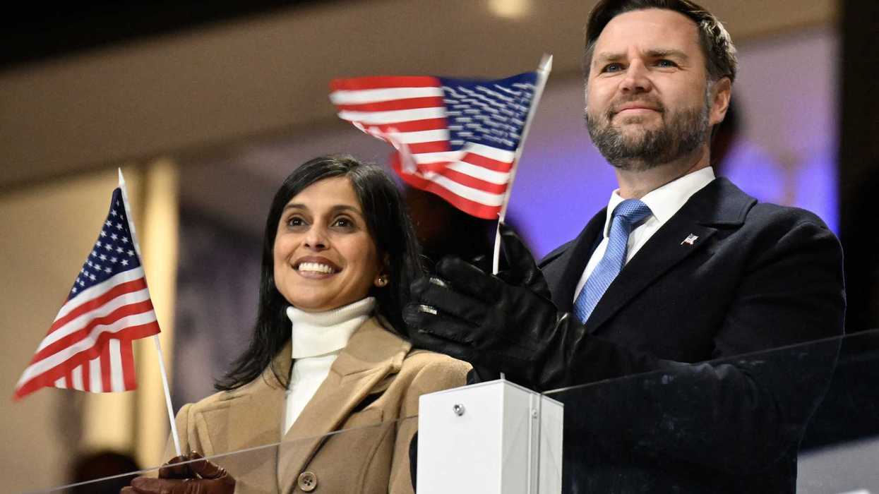 Usha Vance (left) and JD Vance (right) at the Winter Olympics opening ceremony, applauding athletes and holding tiny US flags in their hands.