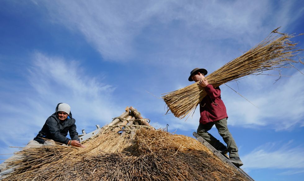 Veteran Jesse Swanson (left) joins Butser Ancient Farm\u2019s Will Scanlan as they thatch the roof (Andrew Matthews/PA)
