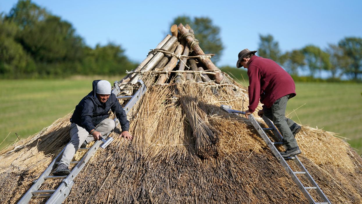 Veteran Jesse Swanson (left) joins Butser Ancient Farm’s Will Scanlan as they thatch the roof of a new Bronze Age roundhouse (Andrew Matthews/PA)