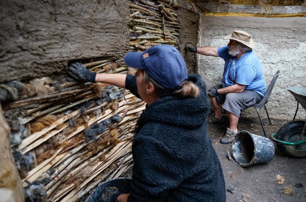 Veterans Kevin Reilly (right) and Jackie Crutchfield apply daub to some wattle in the new Bronze Age roundhouse (Andrew Matthews/PA)