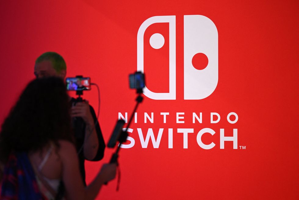Visitors stand in front of a poster of the Nintendo Switch at the Nintendo booth at the Gamescom video game fair in Cologne, western Germany, on August 23, 2023