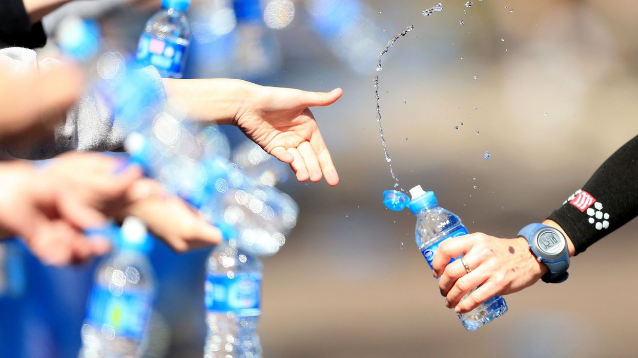 Volunteers offer runners water during the London Marathon (PA)