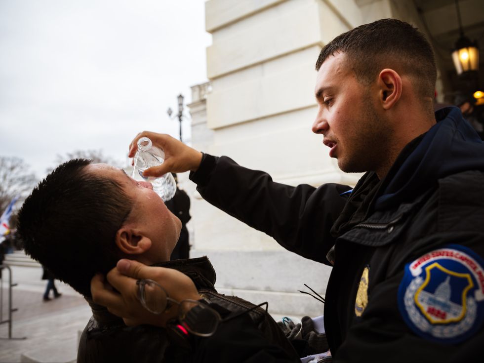 WASHINGTON, DC - JANUARY 06: A pro-Trump protester is tended to by a police officer while suffering the effects of chemical agents used to disperse crows after protesters stormed the grounds the Capitol Building on January 6, 2021 in Washington, DC. A pro-Trump mob stormed the Capitol, breaking windows and clashing with police officers. Trump supporters gathered in the nation's capital today to protest the ratification of President-elect Joe Biden's Electoral College victory over President Trump in the 2020 election. (Photo by Jon Cherry/Getty Images)