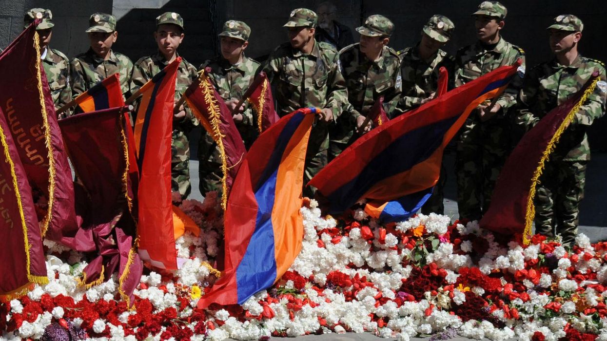 Wearing army-style camouflage costumes young Armenians lower flags as they visit the genocide memorial in Yerevan, 2013